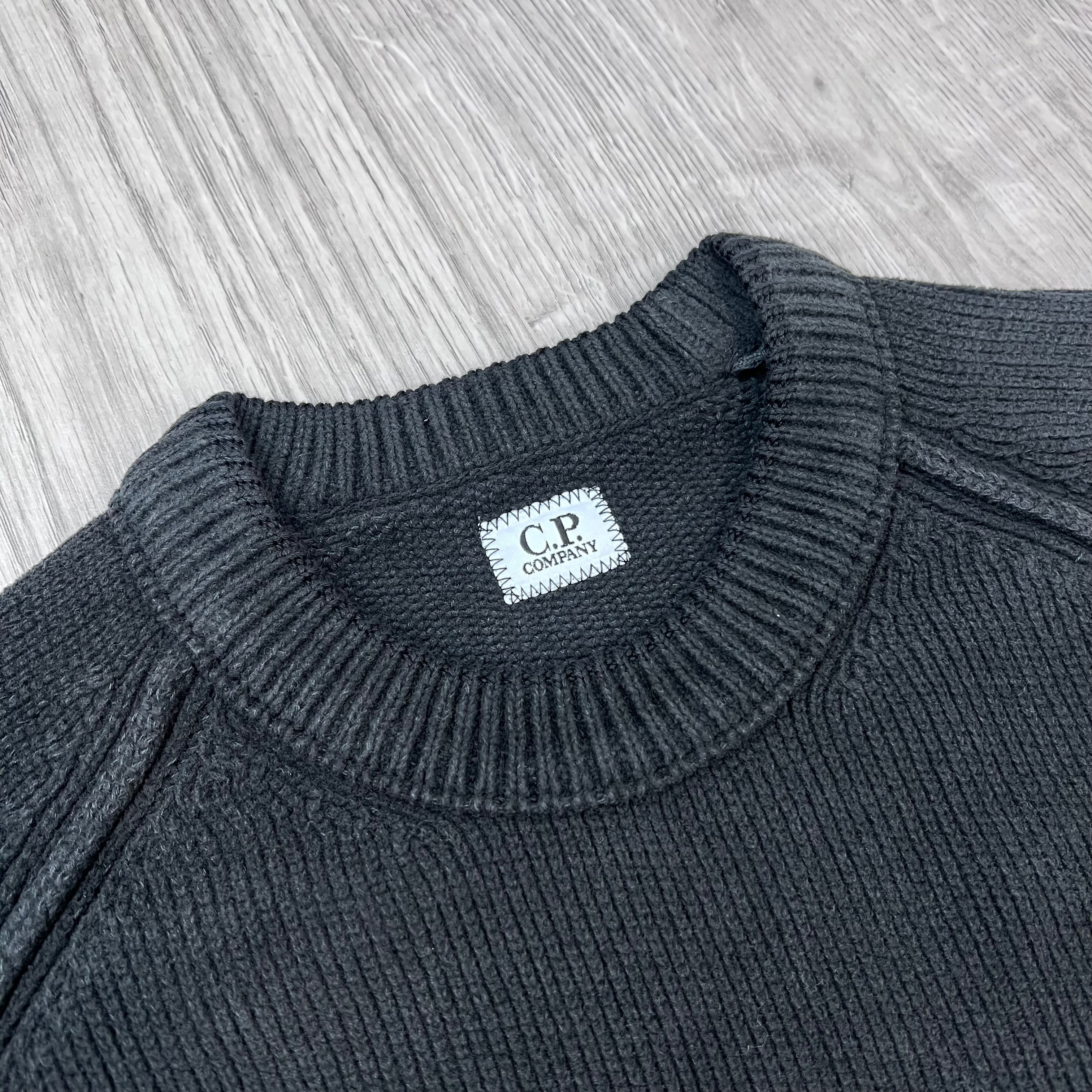 A close view of the crewneck collar on a CP Company Chenille Cotton Lens Sweatshirt in Black.