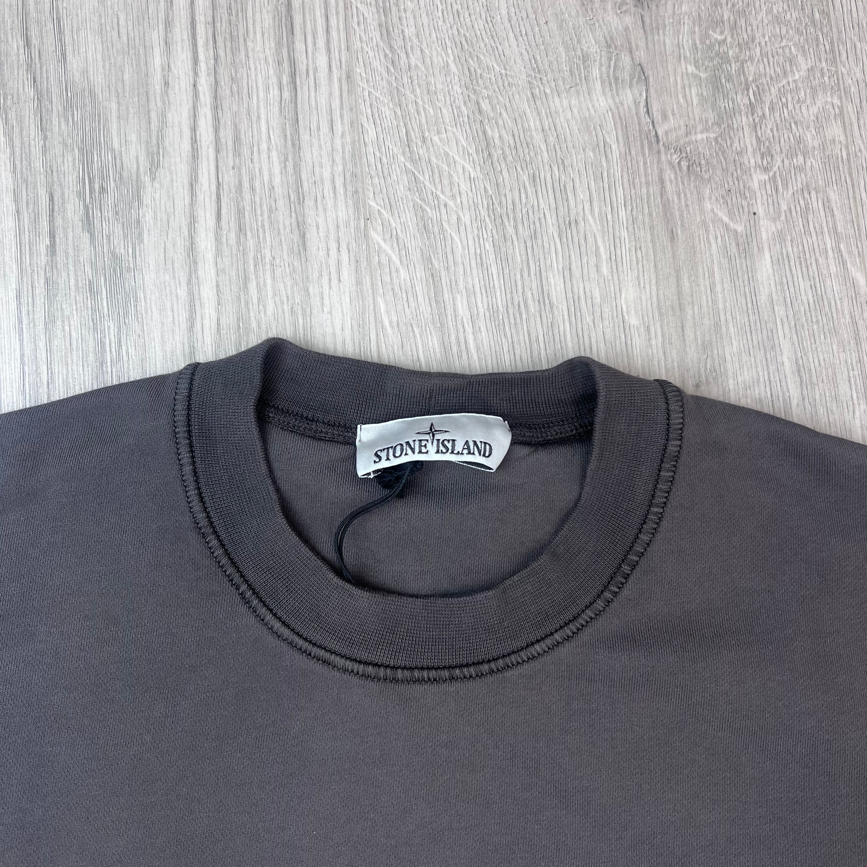 A close up view of the crewneck and label on a Stone Island Crewneck Sweatshirt in Charcoal Grey.