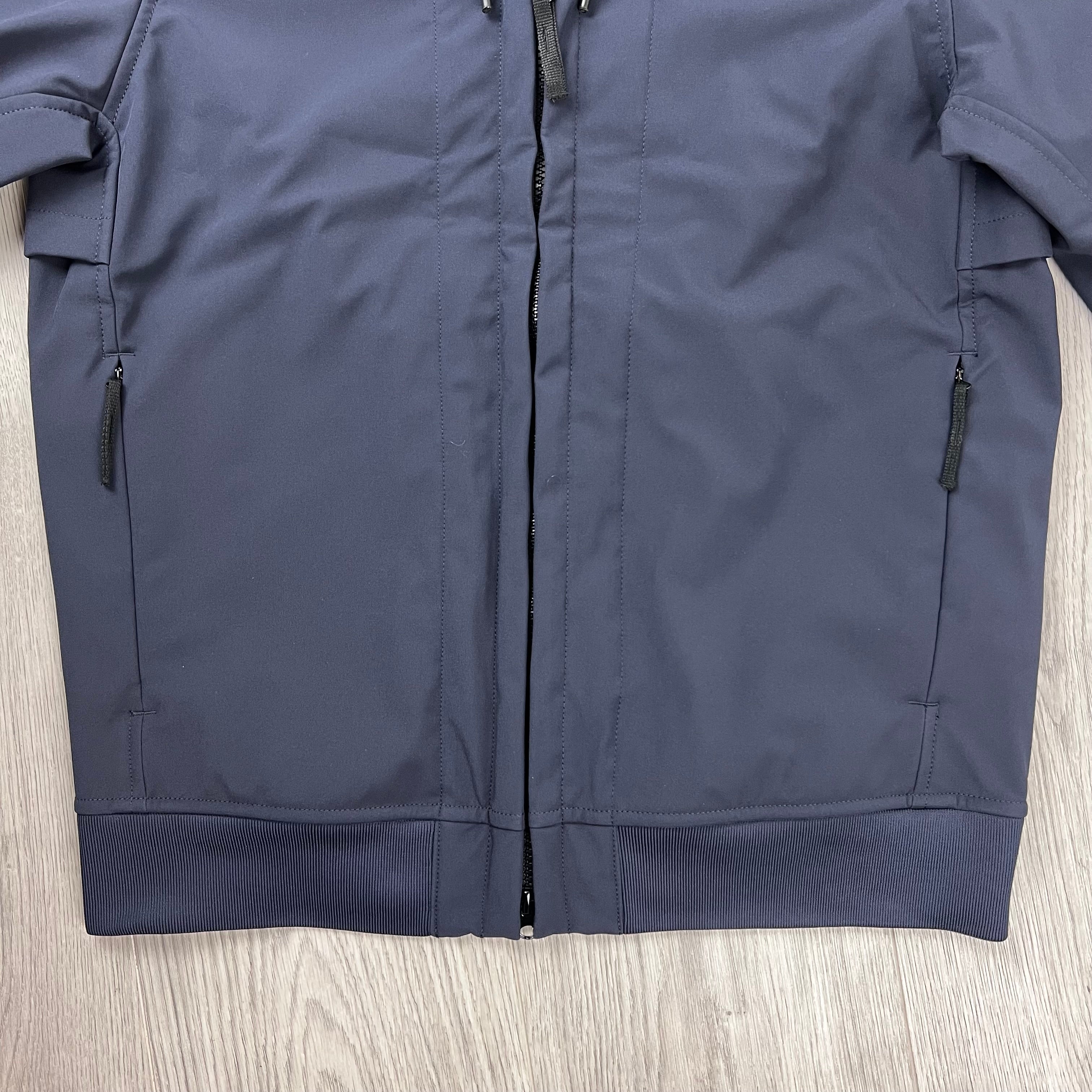 A close up of the Stone Island Soft Shell-Re.dye Jacket in Navy Blue showing the front zipper, side zip pockets, and ribbed hem.