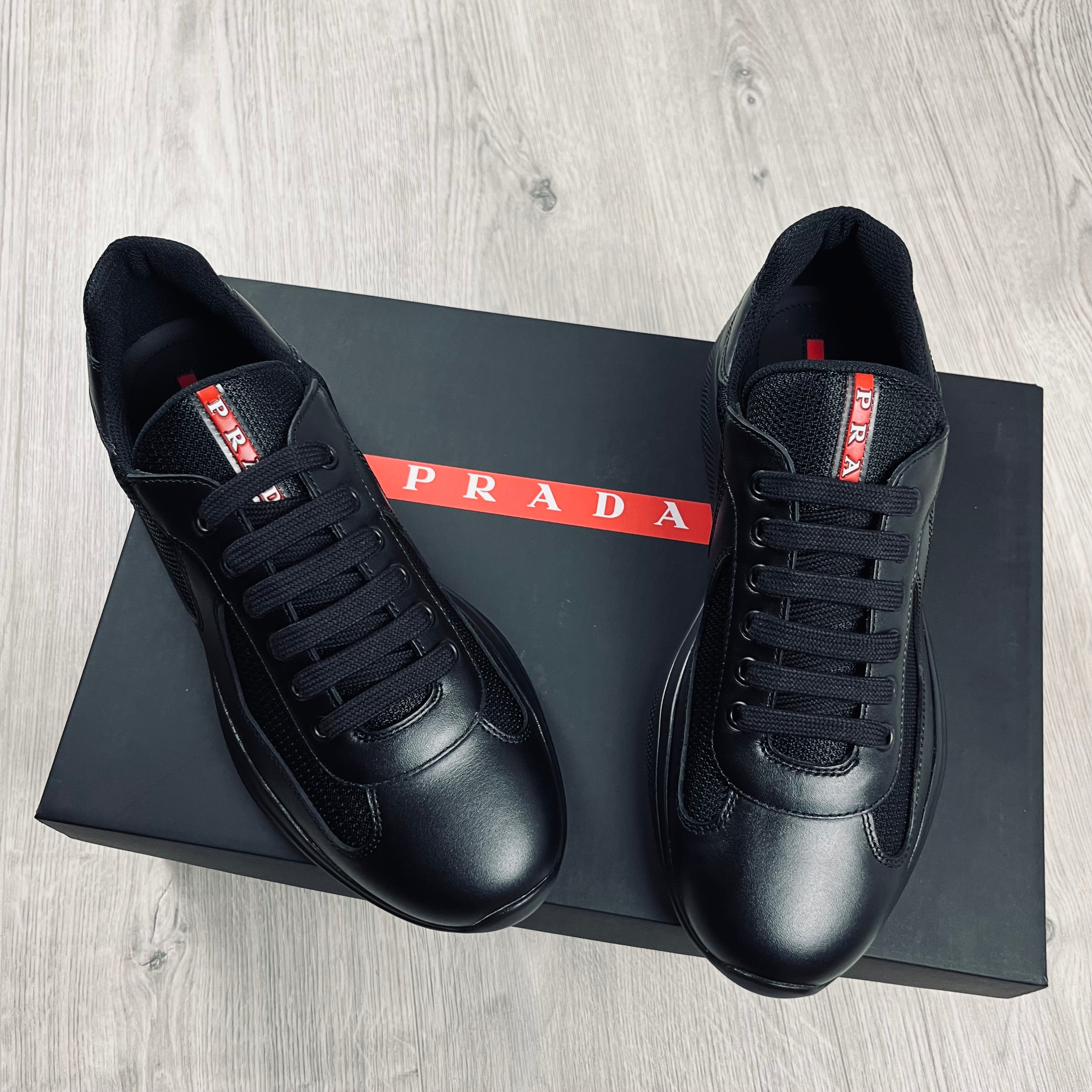 Prada Americas Cup Sneakers in Black. On sale at Open Attire