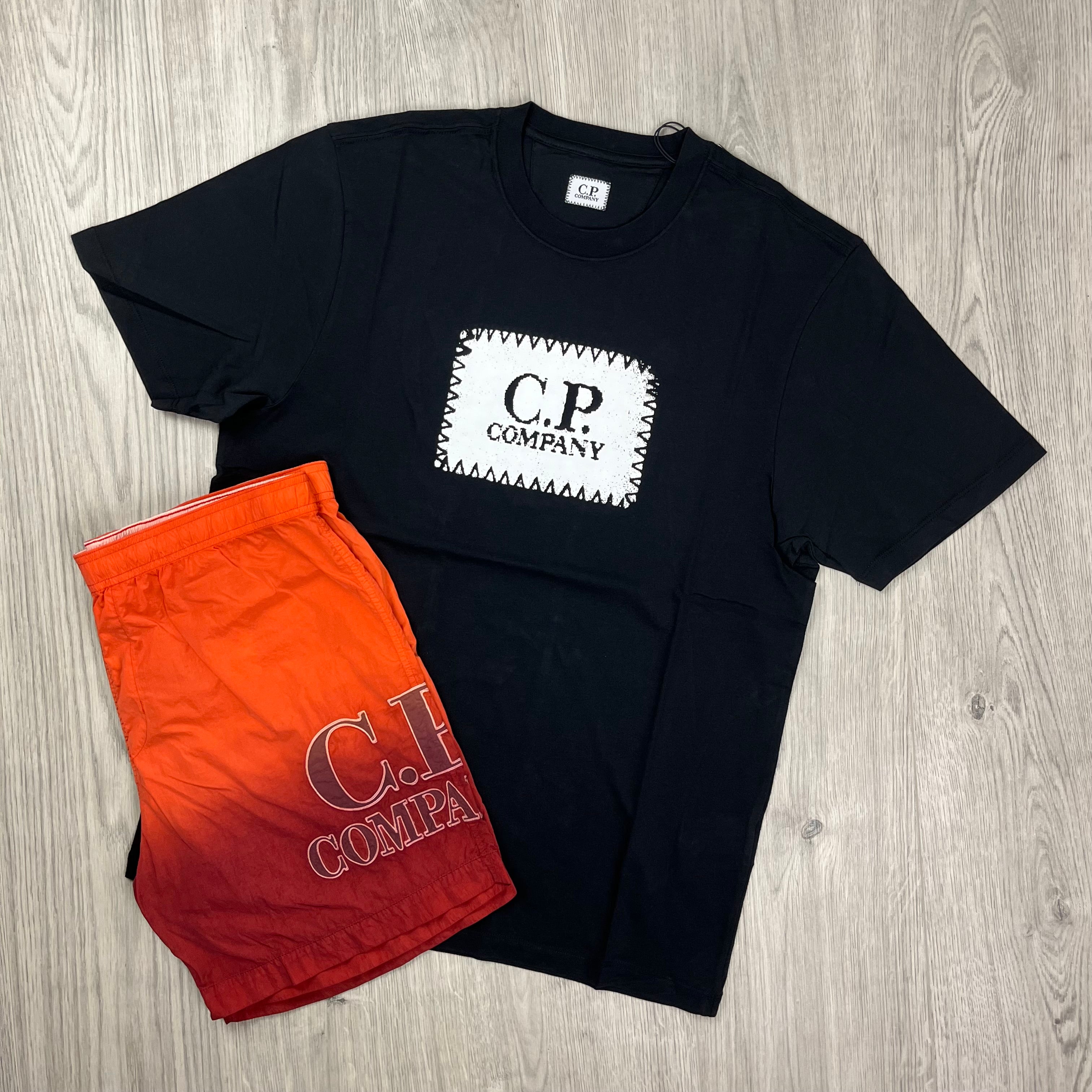 CP Company holiday set consisting of a black T-shirt and orange swimshorts. On sale at Open Attire.