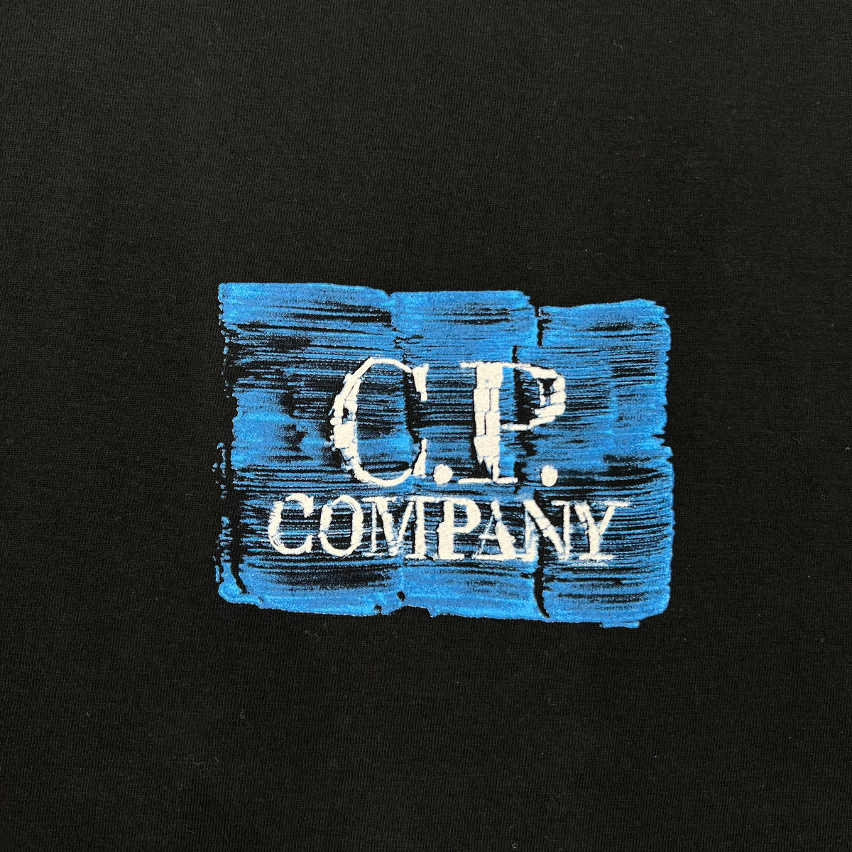 Close up view of the small printed logo on a CP Company 30/1 Jersey Graphics T-Shirt in Black. 