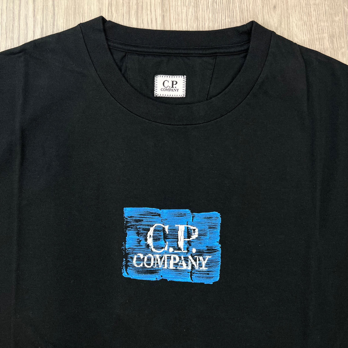 Close up view of the crewneck collar on a CP Company 30/1 Jersey Graphics T-Shirt in Black. 