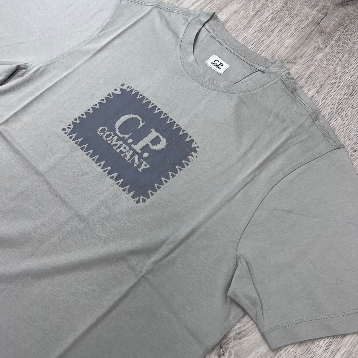 Angled view of the printed logo on a CP Company 30/1 Stamp T-Shirt in Flint Grey.
