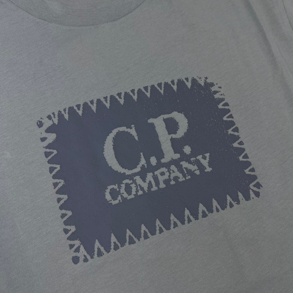 Close up view of the logo on a CP Company 30/1 Stamp T-Shirt in Flint Grey.