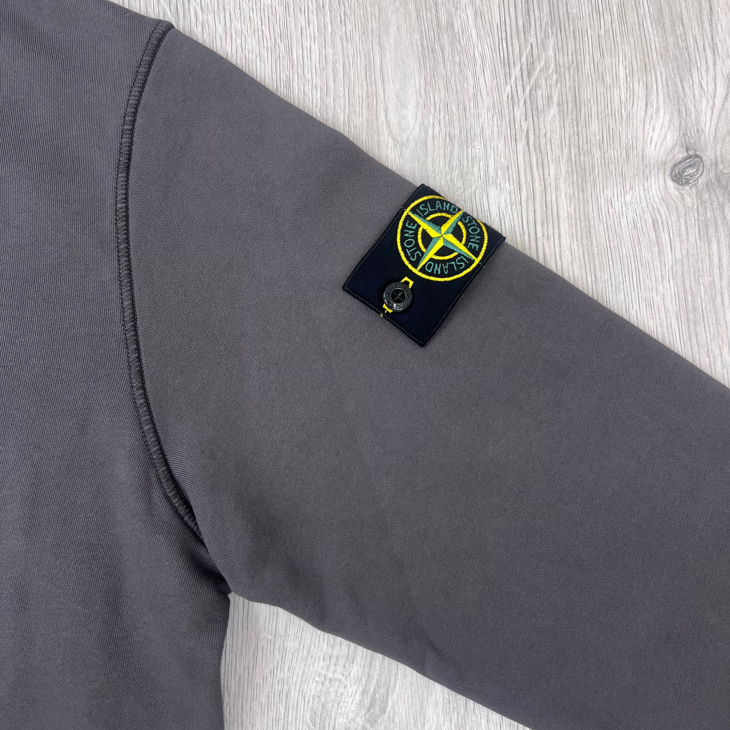 A close up view of the compass badge on a Stone Island Crewneck Sweatshirt in Laurel Green.