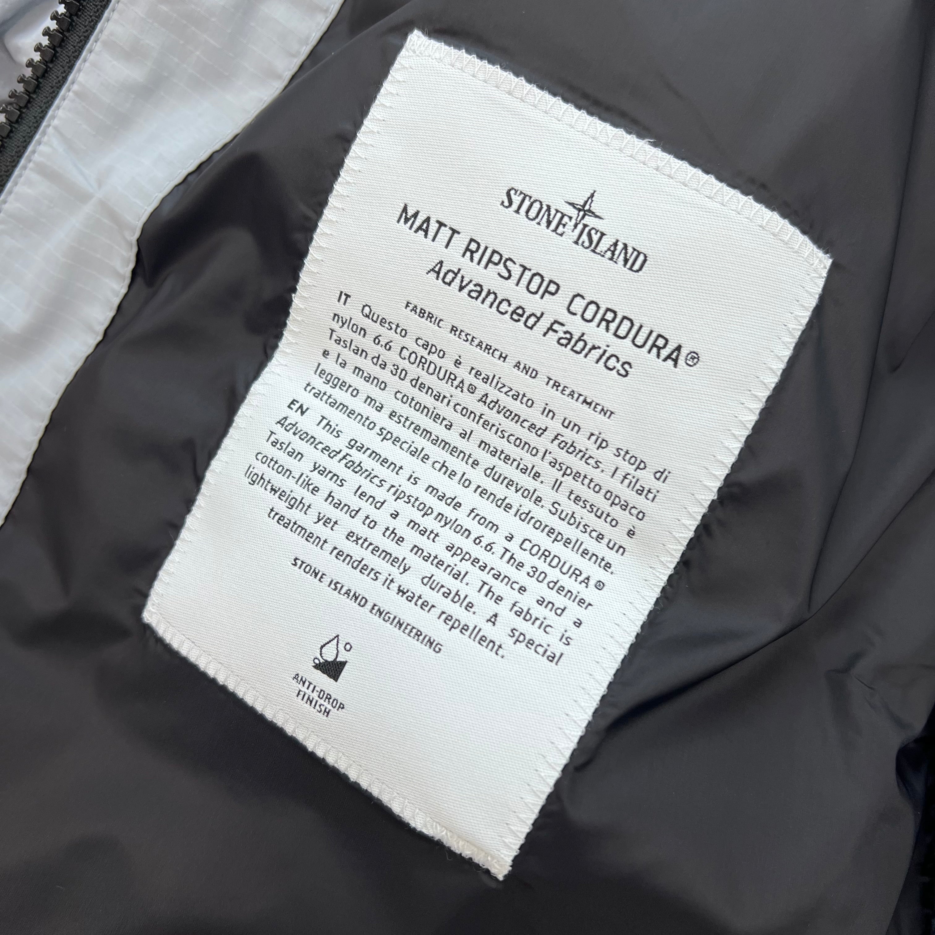 A close up view of the engineering label on a Stone Island Matt Ripstop CORDURA® Down Jacket in Ash Grey.